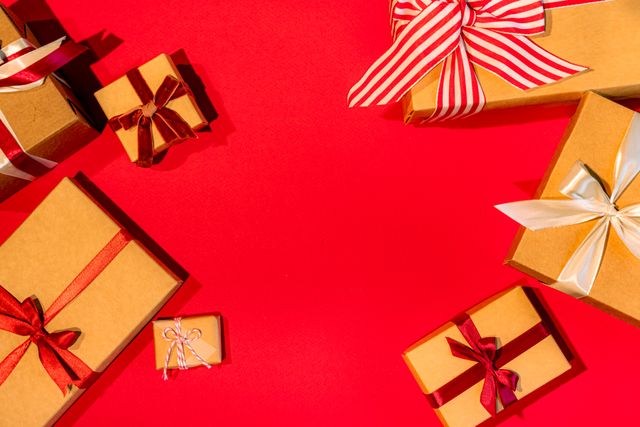 A vibrant flat lay of gift boxes with ribbons on a red surface, perfect for holiday themes.